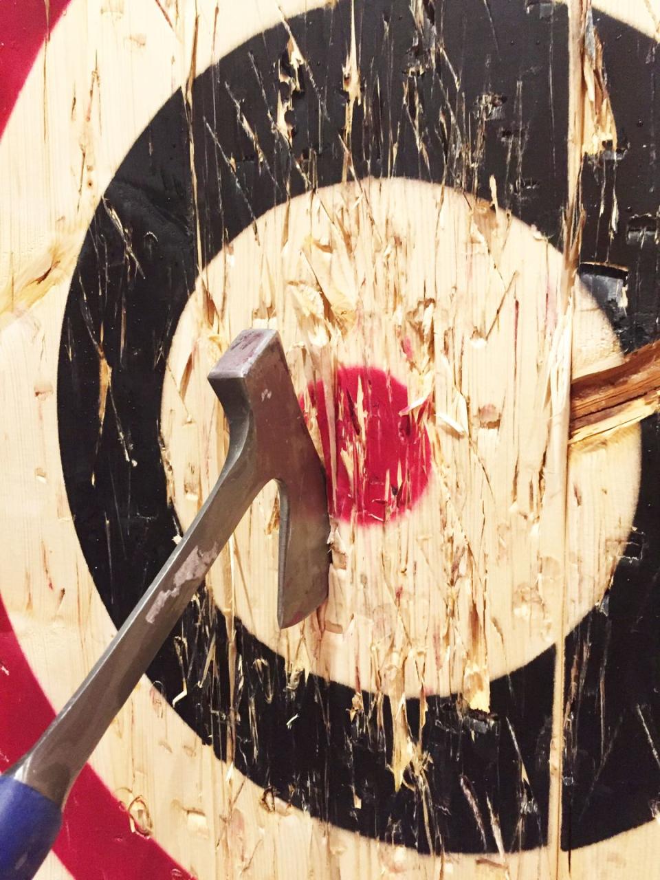 a large metal ax is embedded into a wooden target while playing the game of axe throwing