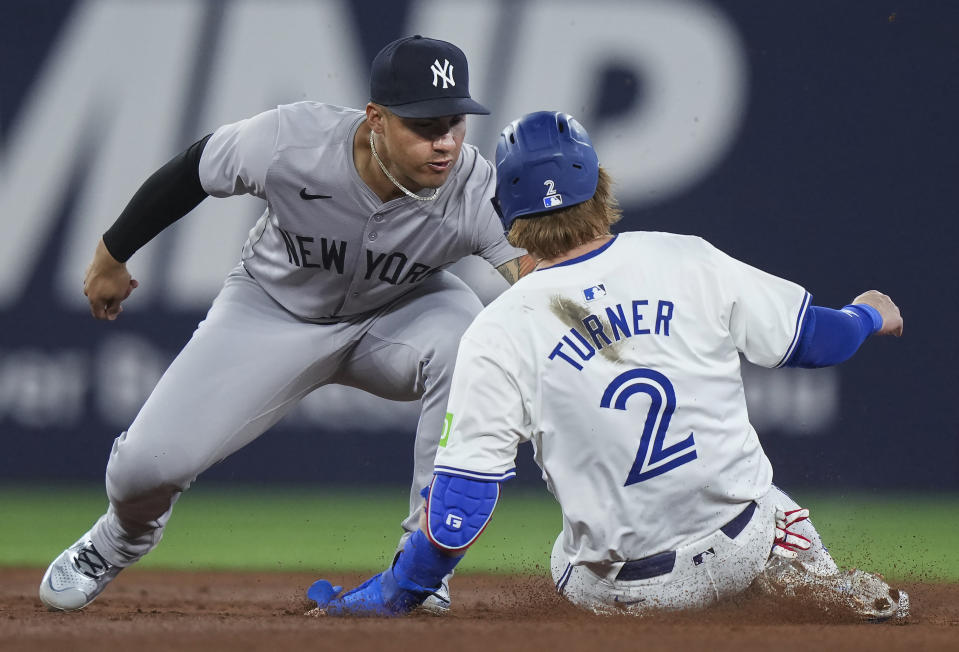 New York Yankees shortstop Anthony Volpe (11) tags out Toronto Blue Jays' Justin Turner (2) on a steal attempt at second base during the fifth inning of a baseball game Tuesday, April 16, 2024, in Toronto. (Nathan Denette/The Canadian Press via AP)