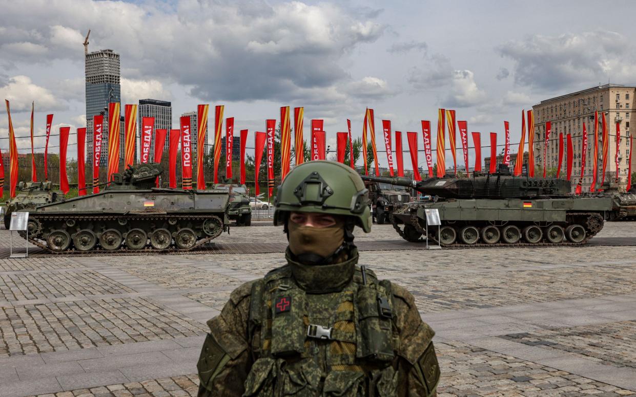 A Russian serviceman stands in front of a German Marder 1A3 infantry fighting vehicle  and a Leopard 2A6 main battle tank