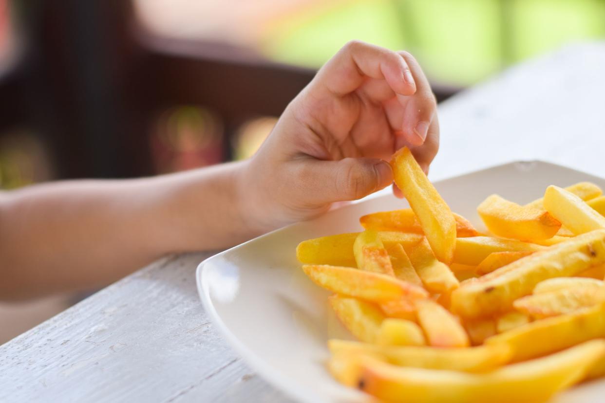 child eating french fries or potato chips.