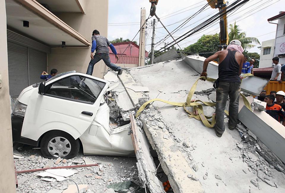 Workers use a crane to lift up concrete block that fell on a car after buildings collapsed during an earthquake in Cebu city, central Philippines October 15, 2013. At least six people were killed when buildings collapsed on islands popular with tourists in the central Philippines on Tuesday, radio reports said, after an earthquake measuring 7.2 hit the region. REUTERS/Stringer (PHILIPPINES - Tags: DISASTER ENVIRONMENT)