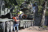 FILE - Workers remove a Soviet T-34 tank installed as a monument in Narva, Estonia, Aug. 16, 2022. Russia's invasion of Ukraine has led to a renewed push to topple the last remaining monuments to the Soviet army that remained in Europe. At the end of the communist era, when Latvia, Lithuania and Estonia regained their independence from the Soviet Union, those countries began renaming streets and toppling statues of Lenin and other communist figures. But many memorials to the Red Army remained. (AP Photo/Sergei Stepanov, File)