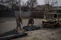 Ukrainian soldiers recover the remains of four killed civilians from inside a charred vehicle in Bucha, outskirts of Kyiv, Ukraine, Tuesday, April 5, 2022. Ukraine’s president plans to address the U.N.’s most powerful body after even more grisly evidence emerged of civilian massacres in areas that Russian forces recently left. (AP Photo/Felipe Dana)