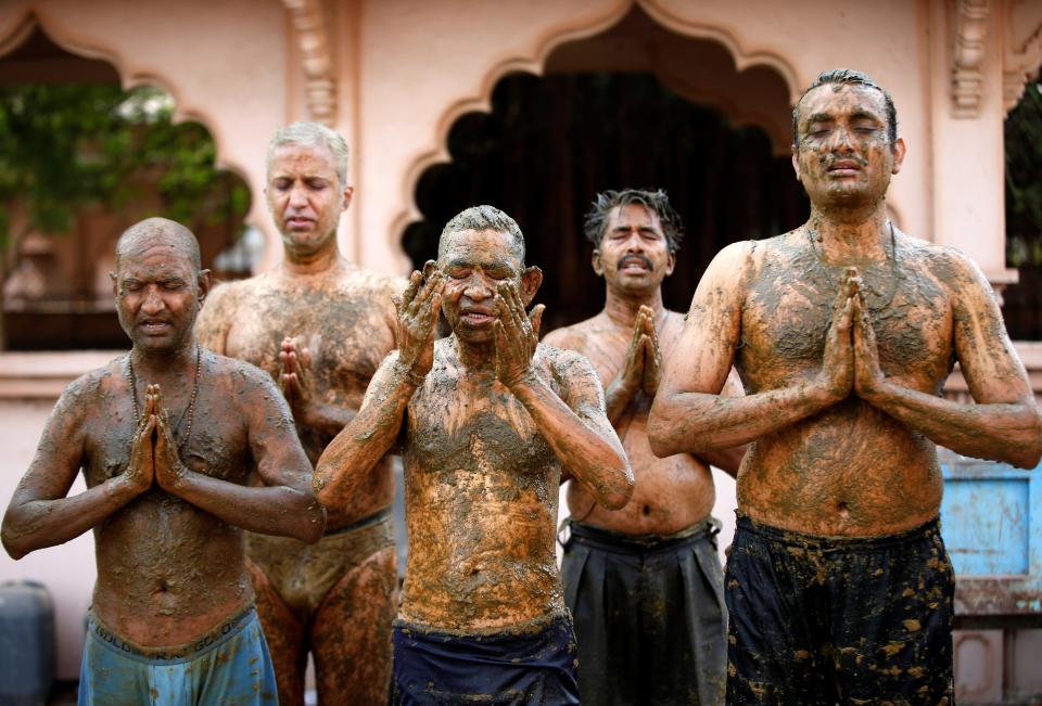 Worshippers pray after applying cow dung to their bodies on the outskirts of AhmedabadReuters