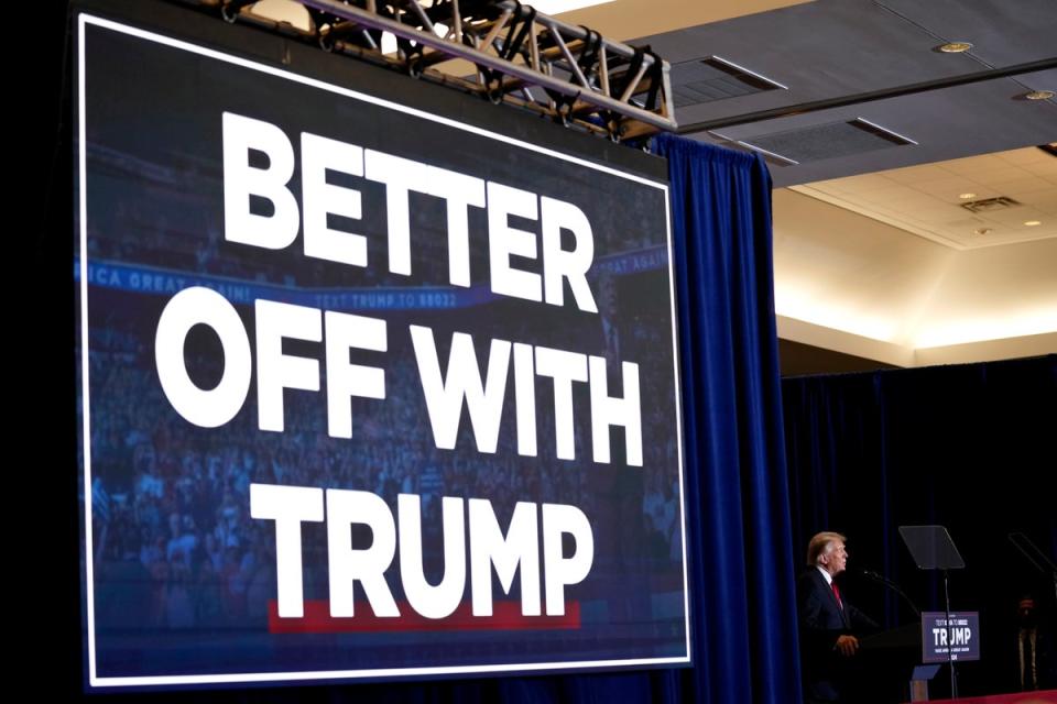 A campaign slogan hangs above Donald Trump as he speaks to supporters in Iowa on 13 December (AP)