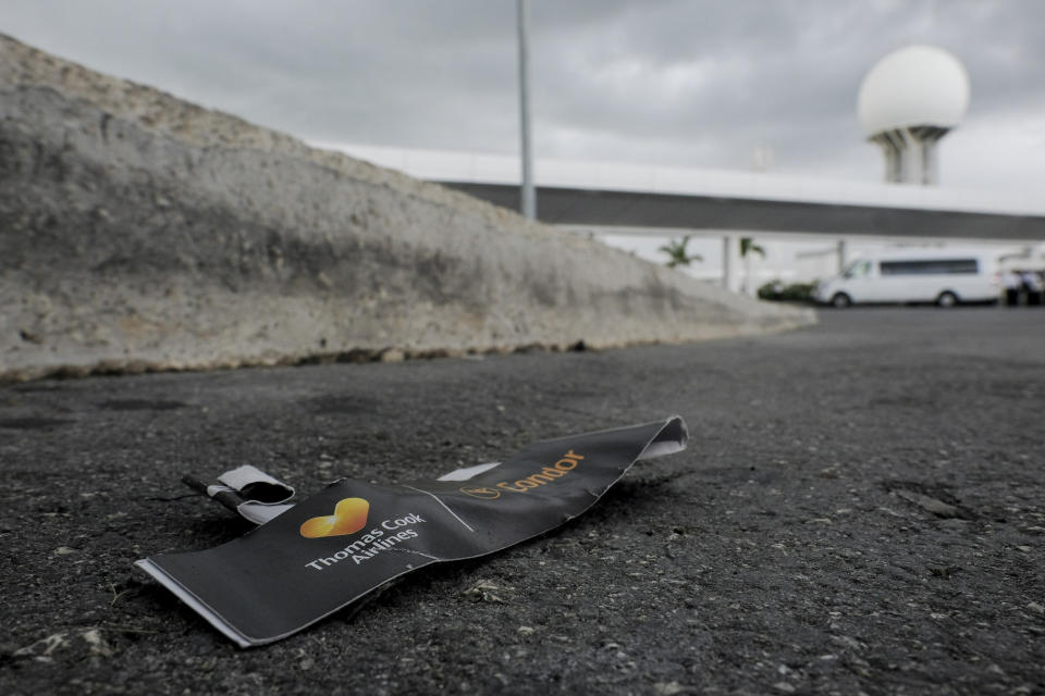 A Thomas Cook luggage tag lays discarded in the street, outside the Cancun airport in Mexico, Monday, Sept. 23, 2019. British tour company Thomas Cook collapsed early Monday after failing to secure emergency funding, leaving tens of thousands of vacationers stranded abroad. (AP Photo/Victor Ruiz)