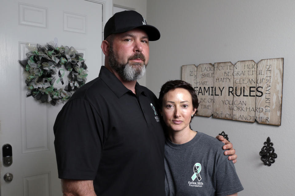 In this Oct. 12, 2021, photo, David and Wendy Mills, parents of Kailee Mills who was killed four years ago in an automobile accident when riding in the back seat without a seat belt, with a photo of their daughter at their home in Spring, Texas. The teenager was riding in the back seat of a car to a Halloween party in 2017 just a mile from her house when she unfastened her seat belt to slide next to her friend and take a selfie. Moments later, the driver veered off the road and the car flipped, ejecting her. (AP Photo/Michael Wyke)