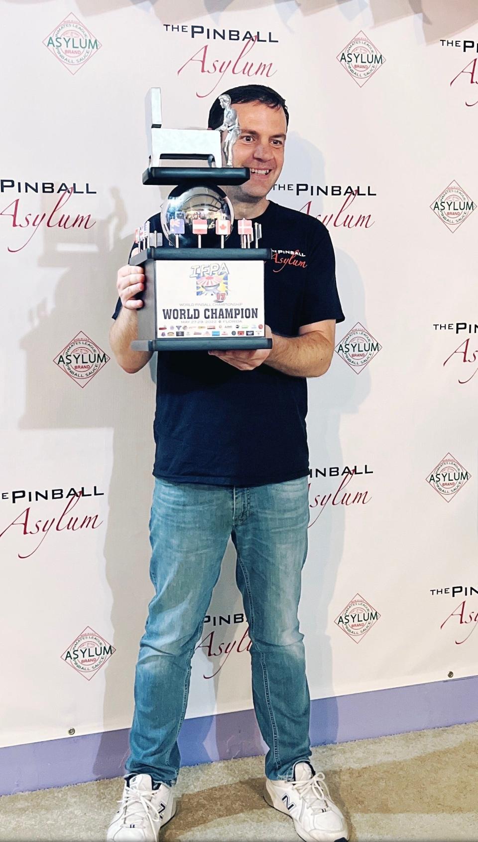 Former WINK News weatherman Eric Stone shows off his world-championship trophy at Fort Myers' The Pinball Asylum. Stone beat 63 other top international players to take first place at the 2022 IFPA World Pinball Championship.