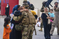 In this image provided by the U.S. Marines, a U.S. Airman with the Joint Task Force-Crisis Response embraces a mother after helping reunite their family at Hamid Karzai International Airport in Kabul, Afghanistan, Friday, Aug. 20, 2021. (Cpl. Davis Harris/U.S. Marine Corps via AP)