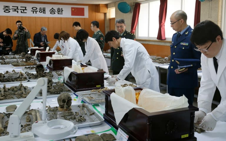 Members of South Korea's Agency for KIA, Killed in Action, Recovery and Identification (in white) prepare the remains of Chinese soldiers, in Paju, on March 28, 2016