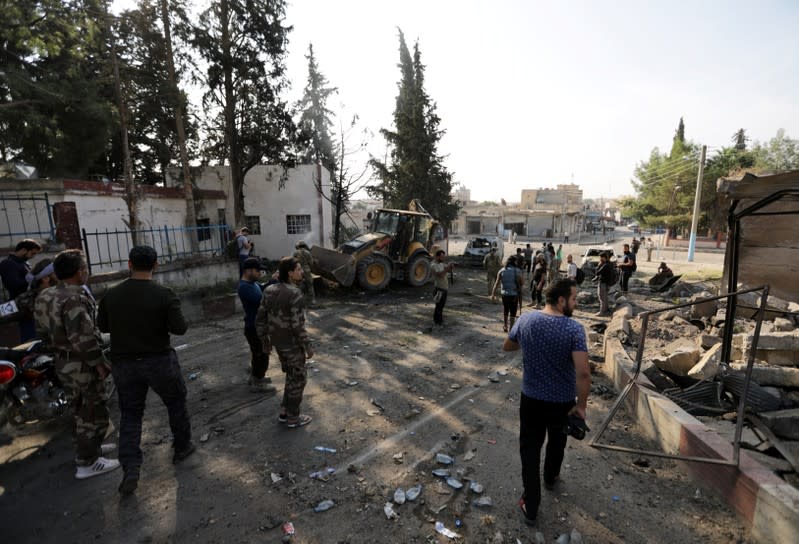 Turkey-backed Syrian rebel fighters inspect the site of an explosion in the town of Tal Abyad