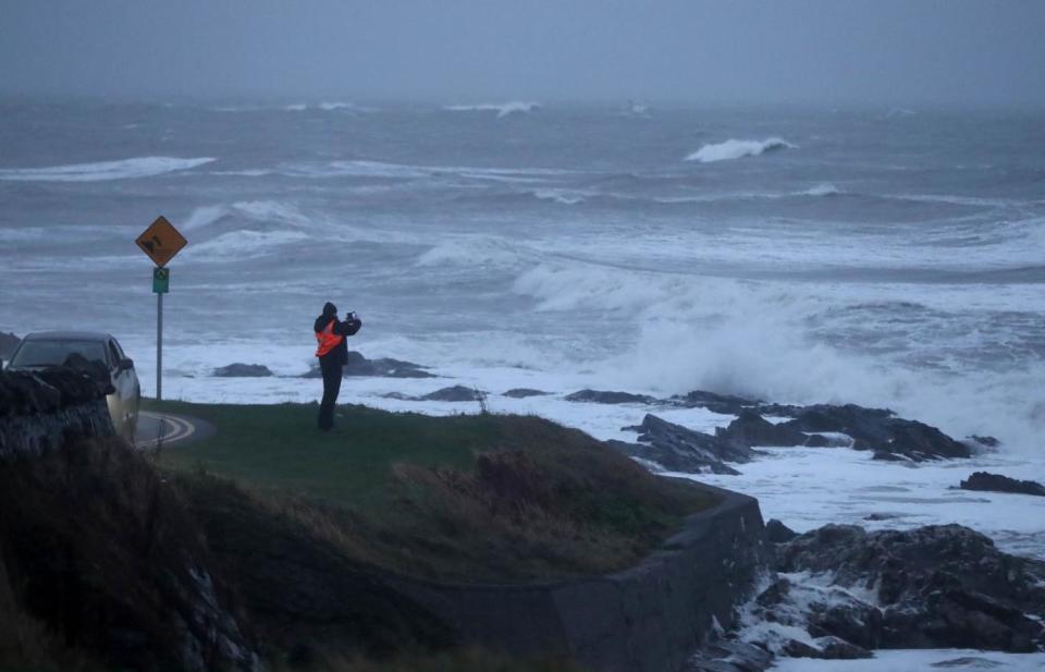 A man photographs waves cause by storm Deirdre in Balbriggan, Co. Dublin, Ireland (PA)