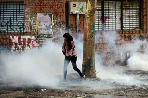 A woman runs away from tear gas after a protest in Santiago turned violent