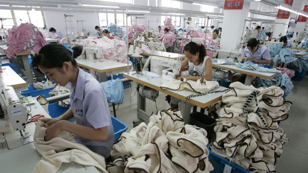 Labourers work on garments for export at the production line of a garment factory in Shanghai