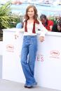 <p>Isabelle Huppert looks comfortable and chic in a pair of vintage-style, light-washed flare jeans and sheer white blouse with a loose red collar. (Photo: Getty) </p>