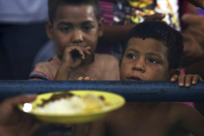 <p>Venezuelan children wait for a free meal at a migrant shelter set up at the Tancredo Neves Gymnasium in Boa Vista, Roraima state, Brazil on March 8, 2018. This is the largest of three shelters for migrants in the city, and has 700 people despite being equipped for 200. (Photo: Eraldo Peres/AP) </p>