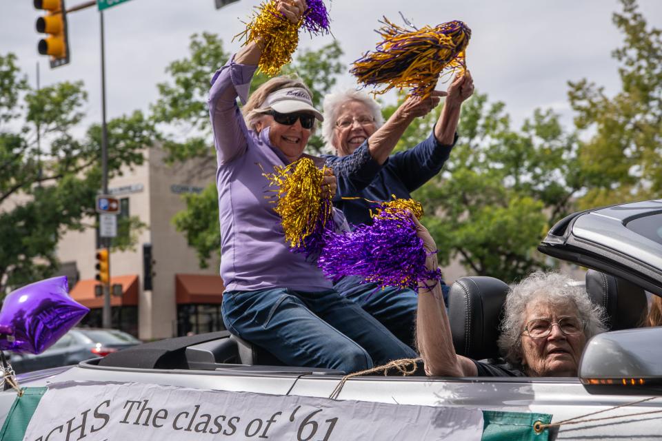 Fort Collins High School classmates Nancy Day and Nancy McMahon Davidson wave pompoms from the back seat of a Mustang convertible with fellow class of 1961 graduate Georgie Bulis Patrick riding in front Saturday as they cruise College Avenue in Fort Collins.