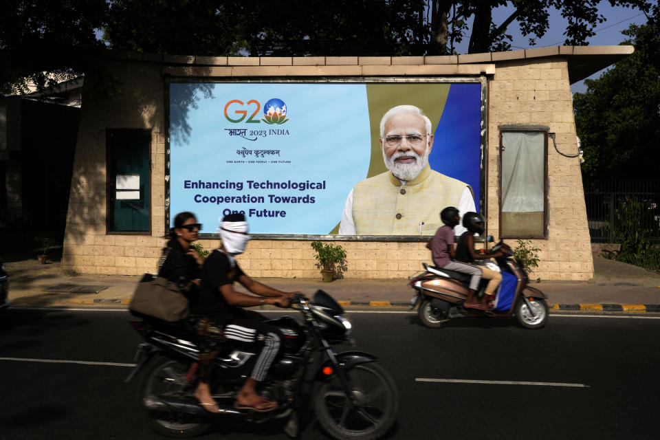 Motorcyclists drive past a billboard featuring Indian Prime Minister Narendra Modi ahead of this week's summit of the Group of 20 nations in New Delhi, India, Monday, Sept. 4, 2023. The Indian government has seized upon its role as host of this year's G20 summit and mounted an advertising blitz that stresses India's growing clout under Prime Minister Narendra Modi. (AP Photo/Manish Swarup)