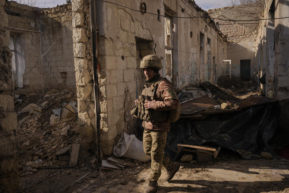 A Ukrainian serviceman walks inside a destroyed house near the frontline village of Krymske, Luhansk region, in eastern Ukraine, Saturday, Feb. 19, 2022. Ukrainian President Volodymyr Zelenskyy, facing a sharp spike in violence in and around territory held by Russia-backed rebels and increasingly dire warnings that Russia plans to invade, on Saturday called for Russian President Vladimir Putin to meet him and seek resolution to the crisis. (AP Photo/Vadim Ghirda)