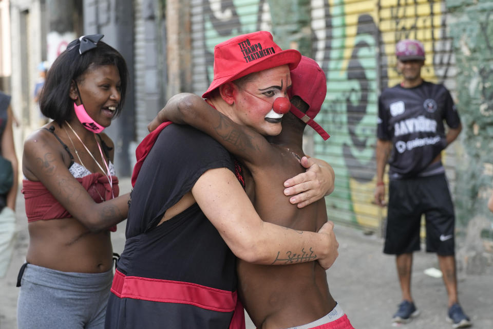 FILE - Flavio Falcone, known as the clown doctor of Crackland, embraces a man during one of his performances in downtown Sao Paulo, Brazil, Thursday, May 11, 2023. Falcone leads a program called "Teto, Trampo e Tratamento" or Roof, Work and Treatment, which carries out social activities with drug users. (AP Photo/Andre Penner, File)
