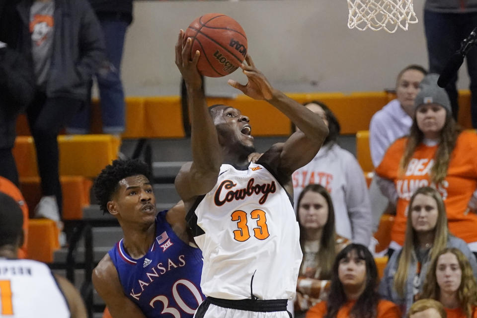 Oklahoma State forward Moussa Cisse (33) shoots in front of Kansas guard Ochai Agbaji (30) in the second half of an NCAA college basketball game Tuesday, Jan. 4, 2022, in Stillwater, Okla. (AP Photo/Sue Ogrocki)