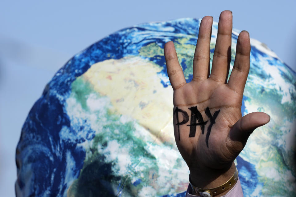 A hand reads "pay" calling for reparations for loss and damage at the COP27 U.N. Climate Summit, Friday, Nov. 18, 2022, in Sharm el-Sheikh, Egypt. (AP Photo/Peter Dejong)