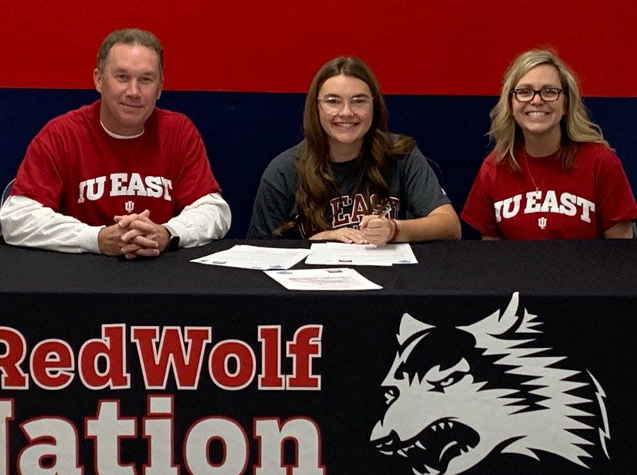 Olivia Sanders (middle) signs her letter of intent to play golf for IU East flanked by her dad, Aaron, and mom, Angie.