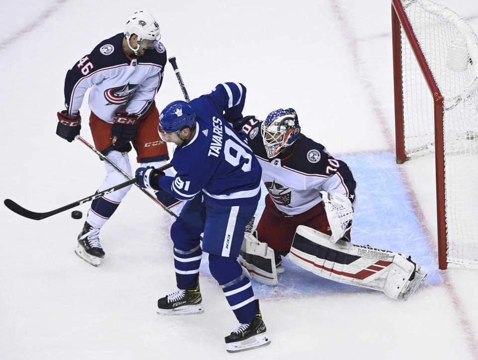 Toronto Maple Leafs center John Tavares (91) tries to tip the puck past Columbus Blue Jackets goaltender Joonas Korpisalo (70) as Blue Jackets defenseman Dean Kukan (46) watches during the second period of an NHL hockey playoff game in Toronto, Sunday, Aug. 2, 2020. (Nathan Denette/The Canadian Press via AP)