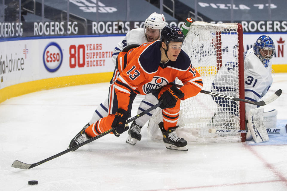 Edmonton Oilers' Jesse Puljujarvi (13) and Toronto Maple Leafs' Morgan Rielly (44) work for the puck during the second period of an NHL hockey game Wednesday, March 3, 2021, in Edmonton, Alberta. (Jason Franson/The Canadian Press via AP)