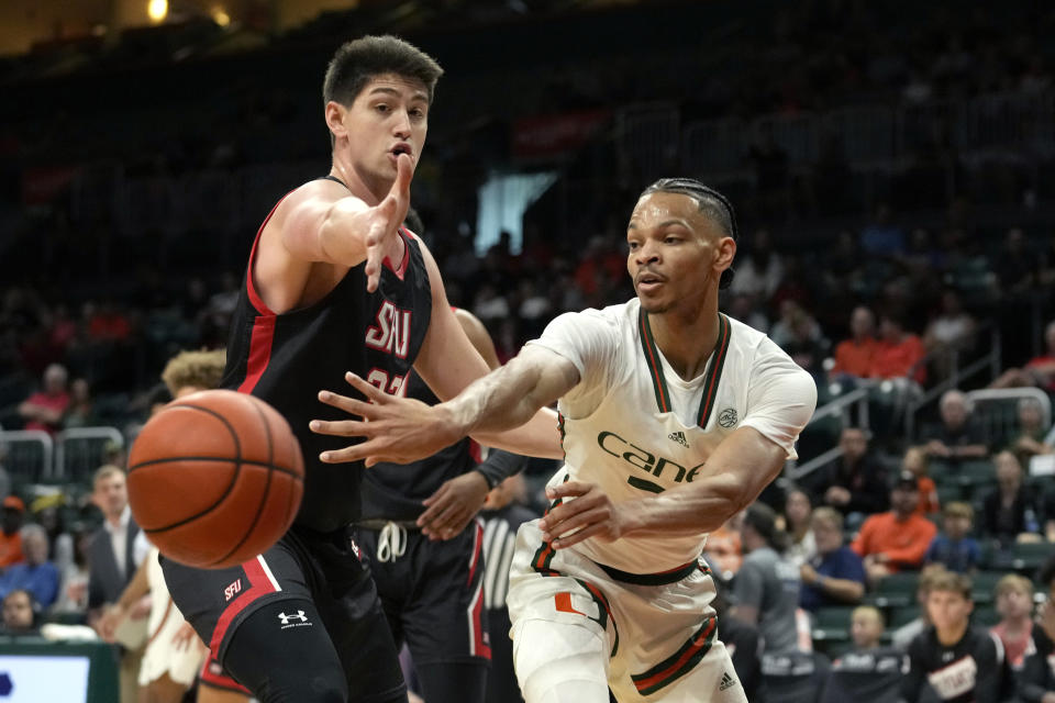 Miami guard Isaiah Wong, right, passes the ball as St. Francis forward Josh Cohen defends during the first half of an NCAA college basketball game, Saturday, Dec. 17, 2022, in Coral Gables, Fla. (AP Photo/Lynne Sladky)