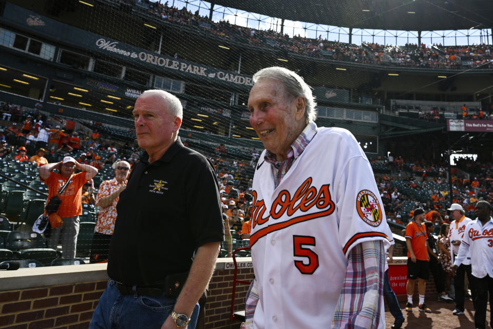 Former Baltimore Orioles third baseman Brooks Robinson, right, walks onto the field before a baseball game between the Baltimore Orioles and the Pittsburgh Pirates, Saturday, Aug 6, 2022, in Baltimore. (AP Photo/Terrance Williams)