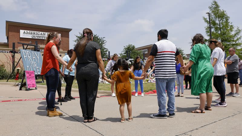 People hold hands as they pray at a memorial for victims of the Allen Premium Outlets mass shooting, Tuesday, May 9, 2023, in Allen, Texas.