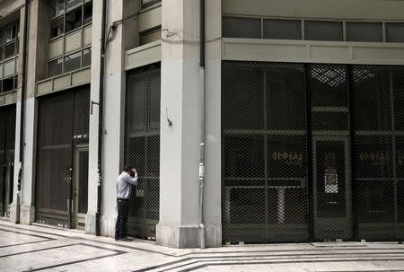 A man looks through the window of a closed shop in an arcade, where most shops closed since the beginning of the Greek financial crisis, in central Athens April 17, 2015. REUTERS/Alkis Konstantinidis