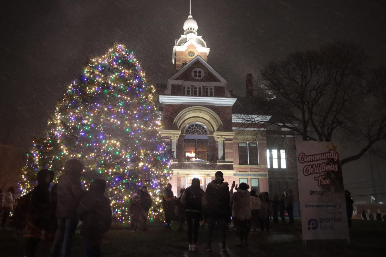 Snow falls as people enjoy the Community Christmas Tree at the old Lenawee County Courthouse in Adrian shortly after it was lighted Monday.