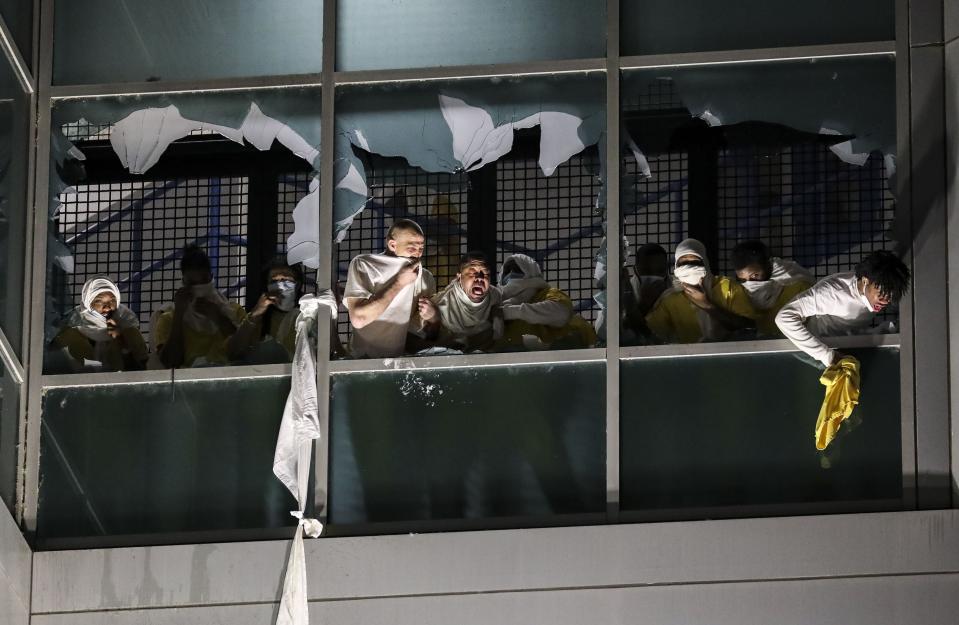 Inmates, from a second cell block, cough and try to breath through broken windows after officers deploy a chemical irritant at the St. Louis Justice Center, known as the city jail, on Sunday, April 4, 2021. Inmates broke windows, set a fire and threw debris to the ground late Sunday at a St. Louis jail that has been plagued by uprisings in recent months. (Colter Peterson/St. Louis Post-Dispatch via AP)