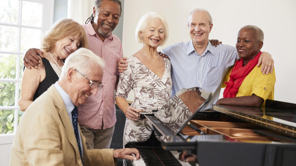  Older people singing around a piano. 