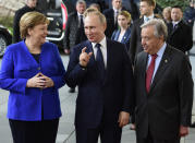 German Chancellor Angela Merkel, left, greets United Nations Secretary General Antonio Guterres, right, and Russian President Vladimir Putin, center, during arrivals for a conference on Libya at the chancellery in Berlin, Germany, Sunday, Jan. 19, 2020. German Chancellor Angela Merkel hosts the one-day conference of world powers on Sunday seeking to curb foreign military interference, solidify a cease-fire and help relaunch a political process to stop the chaos in the North African nation. (AP Photo/Jens Meyer)