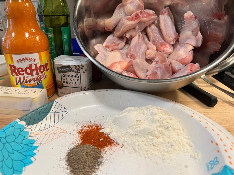 Chicken wings in bowl next to plate of spices