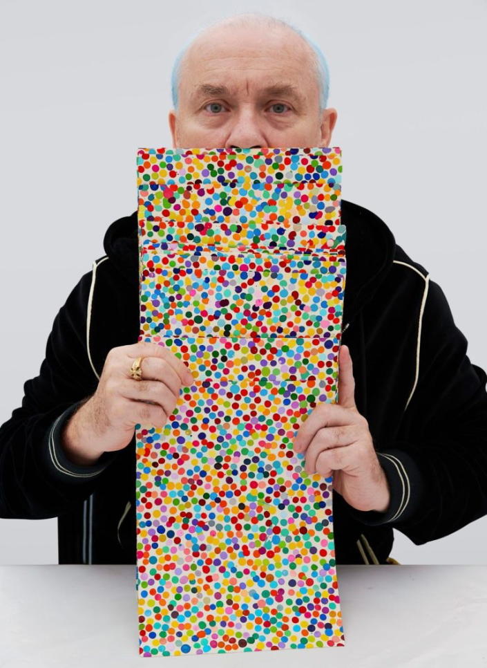 Damien Hirst holds up physical versions of 