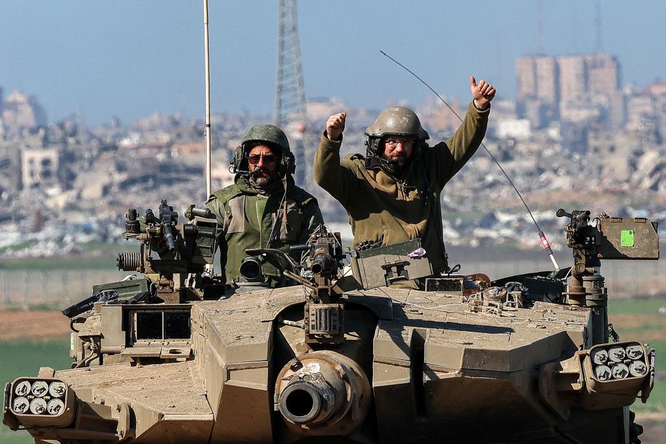 An Israeli army soldier gestures while seated in the turret of a battle tank moving at a position along the border between southern Israeli and the Gaza Strip on January 31, 2024.