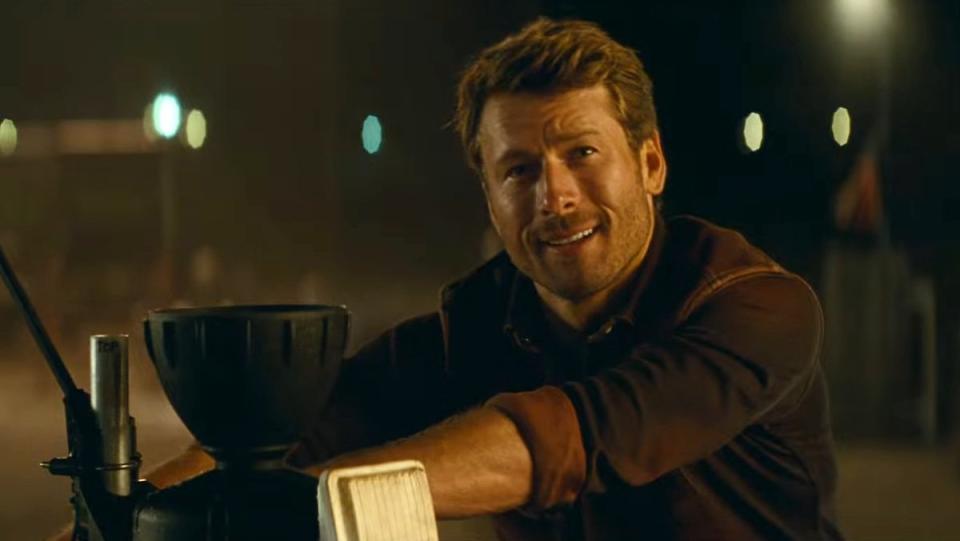Glen Powell smiles atop a truck in Twisters