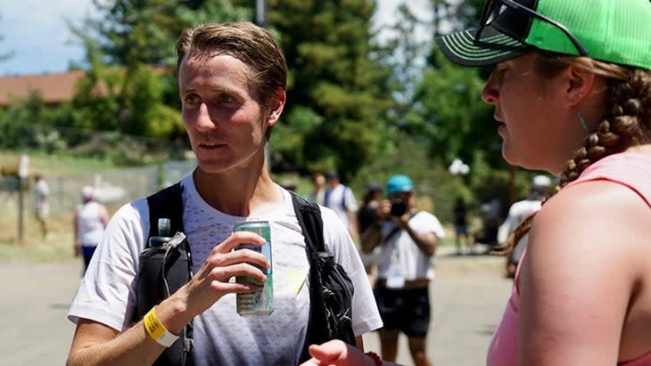 a man drinks a cold beverage on the Western States 100 course