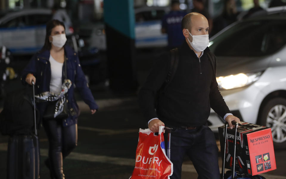 Passengers wearing masks as a precaution against the spread of the new coronavirus COVID-19 arrive to the Sao Paulo International Airport in Sao Paulo, Brazil, Wednesday, Feb. 26, 2020. (AP Photo/Andre Penner)