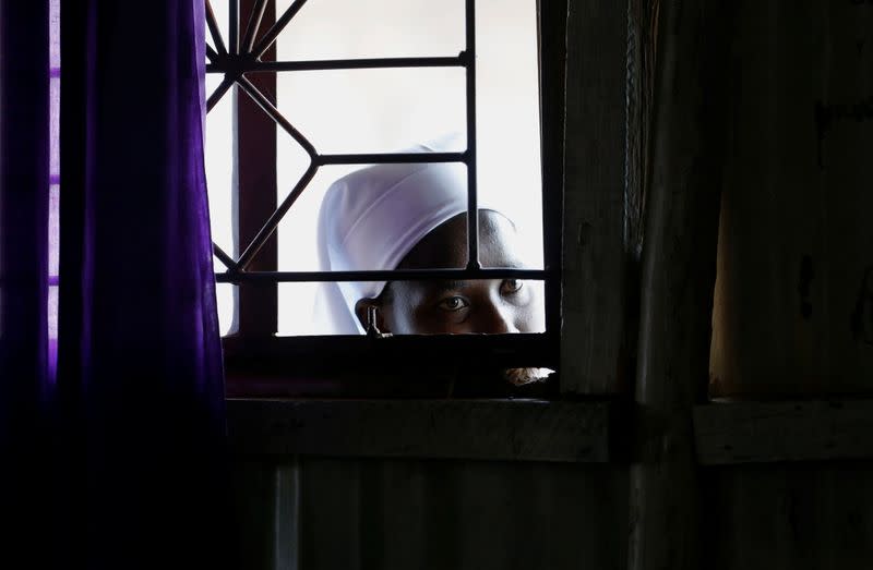 A faithful looks through the window as she follows a mass, amid concerns about the spread of coronavirus disease (COVID-19) at the St. Joanes, Legio Maria African Mission Church within Fort Jesus in Kibera slums of Nairobi