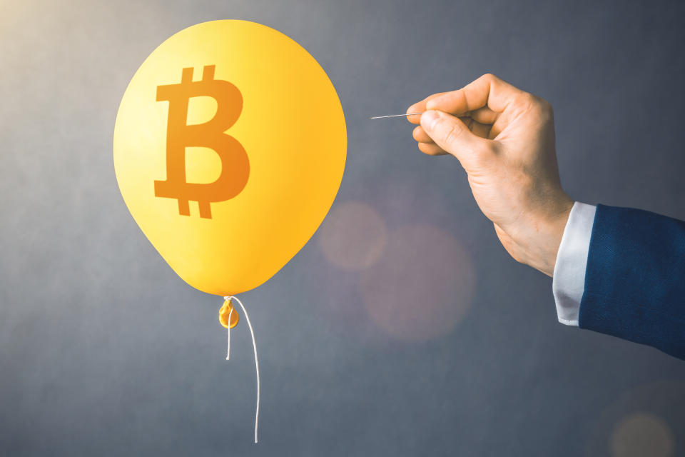 Bitcoin symbol on yellow balloon. Man with needle about to pop it.