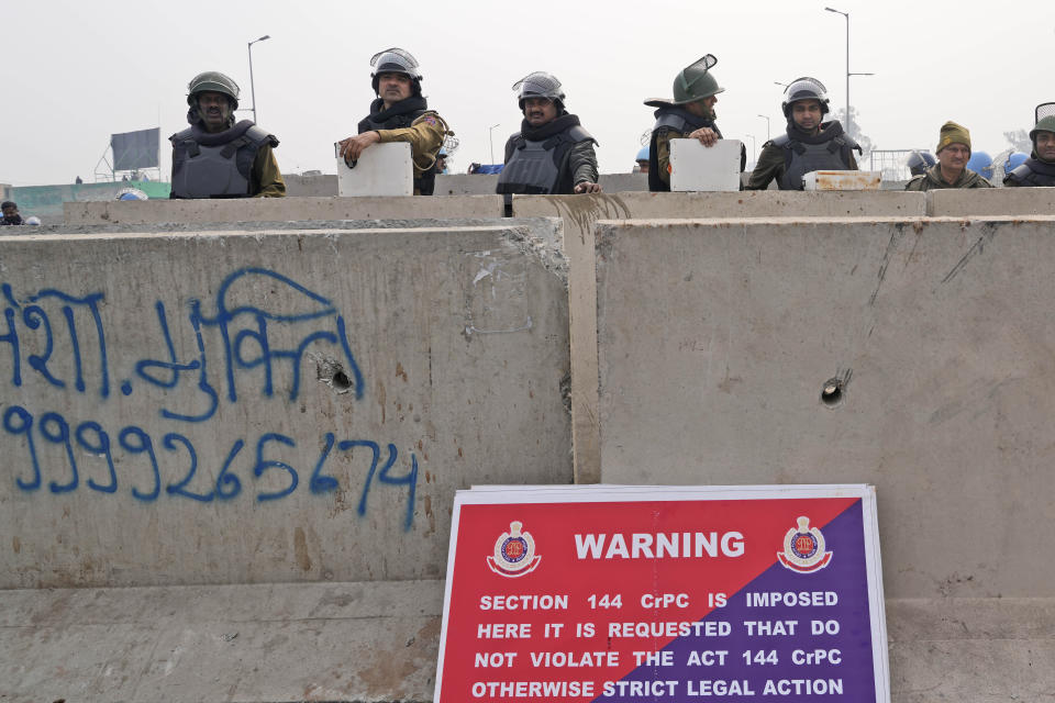 Delhi police in riot gear guard a major highway at Singhu near New Delhi to stop thousands of protesting farmers from entering the capital, India, Tuesday, Feb.13, 2024. Farmers, who began their march from northern Haryana and Punjab states, are asking for a guaranteed minimum support price for all farm produce. (AP Photo/Manish Swarup)