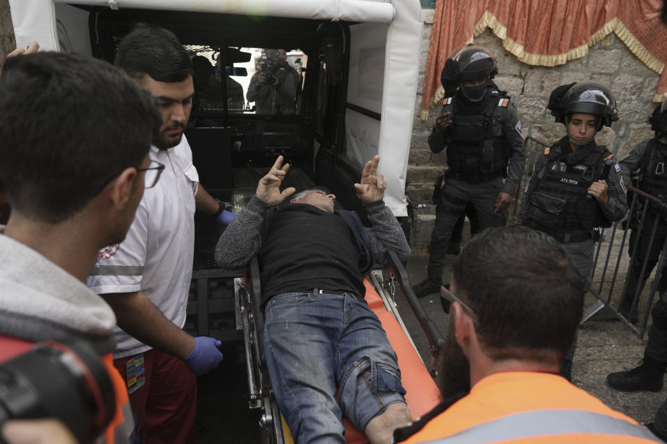 Paramedics carry an injured Palestinian in the Old City of Jerusalem, Sunday, April 17, 2022. Israeli police clashed with Palestinians outside Al-Aqsa Mosque after police cleared Palestinians from the sprawling compound to facilitate the routine visit of Jews to the holy site and accused Palestinians of stockpiling stones in anticipation of violence. (AP Photo/Mahmoud Illean)