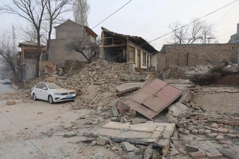 A vehicle is partially covered by a collapsed building in the aftermath of an earthquake in Dahejia village of Jishishan county in northwestern China's Gansu province Tuesday, Dec. 19, 2023. An overnight earthquake killed multiple people in a cold and mountainous region in northwestern China, the country's state media reported Tuesday.(Chinatopix via AP)