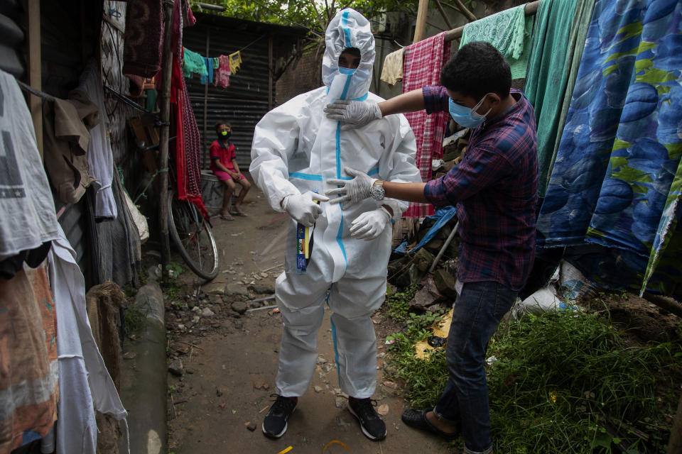 A heath worker helps another to wear protective suit before collecting swab samples of people to test for COVID-19 in Gauhati, Assam, India, Monday, May 17, 2021. (AP Photo/Anupam Nath)