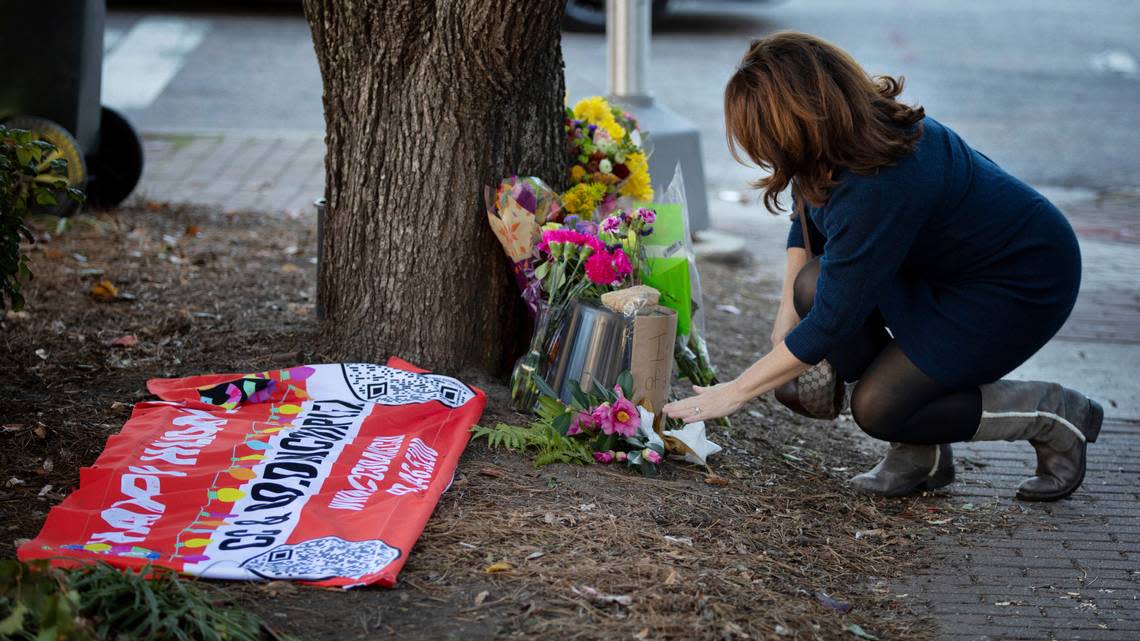 Tonya Mills reaches out to gently touch the memorial for an 11-year-old girl killed by an out-of-control truck Saturday, Nov. 19, 2022, in the Raleigh Christmas Parade. The girl, Hailey Brooks, was a member of the CC & Co. Dance complex and their banner from the parade is on the ground at the memorial. Mills’ son was marching in the parade just ahead of the dance troupe.